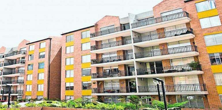 Fachada de edificio de ladrillos, balcones negros y ventanas amarillas 