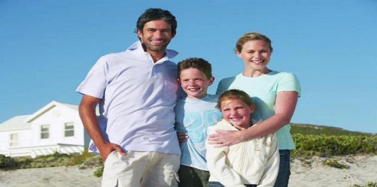 Familia feliz con casa de playa de fondo