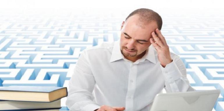 Hombre preocupado con libros y computador en escritorio