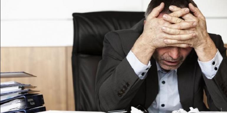 Hombre-preocupado-con-manos-en-la-cabeza-y-papeles-alrededor