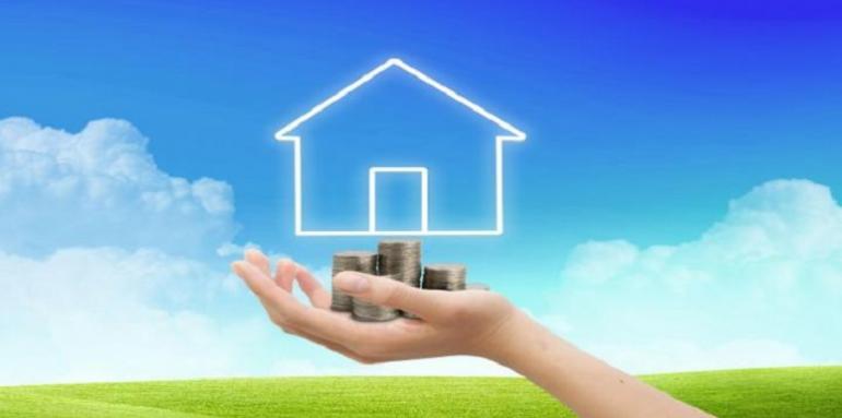 Mano sosteniendo monedas con casa pintada en el cielo