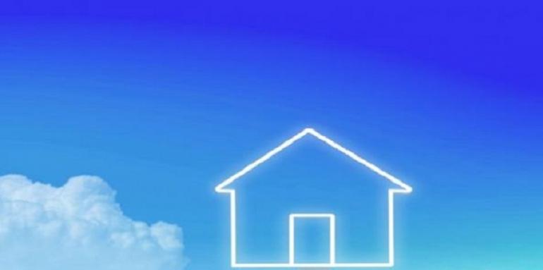 Mano sosteniendo monedas con casa pintada en el cielo