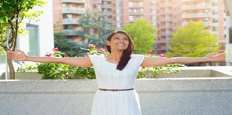 Mujer extendiendo los brazos delante de edificios