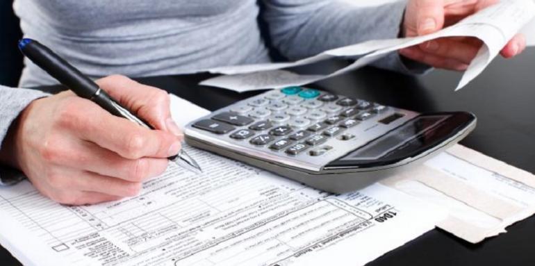 Mujer llenando formulario usando calculadora
