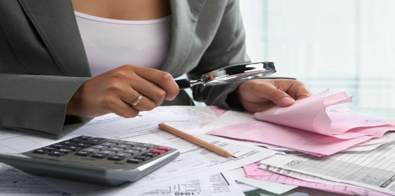 Mujer revisando con lupa recibos 