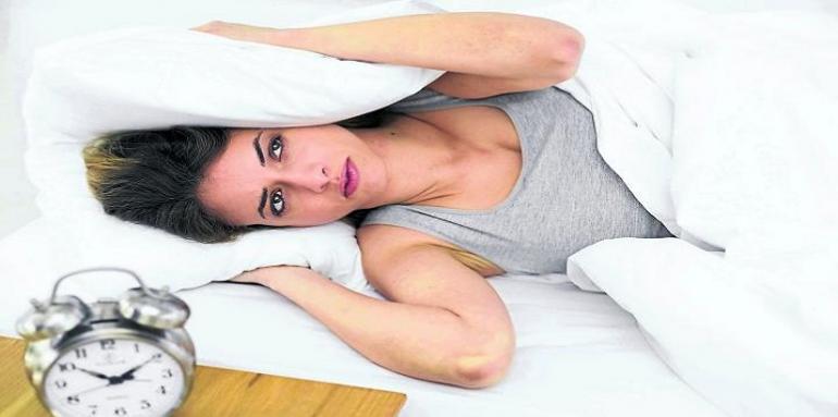 Mujer tapandose los oidos con almohadas