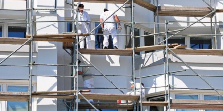 Obreros sobre andamio en edificio blanco