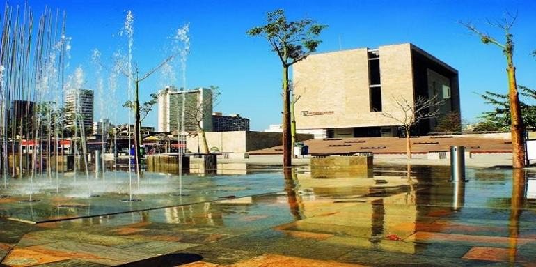Parque con fuentes de agua con edificio cubico de fondo
