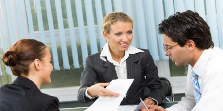 Reunión en oficina dos mujeres un hombre revisando papeles 