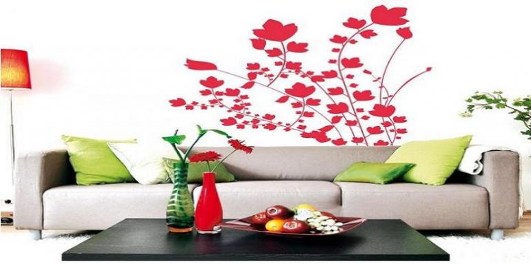 Sala con pared blanca vinillo de flores rojas y sofácama color crema