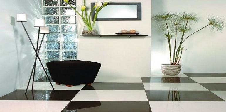 Sala con piso negro y blanco, mueble negro, plantas y velas