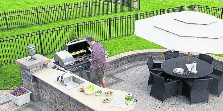 Terraza con parrilla y mesa de campo con hombre cocinando