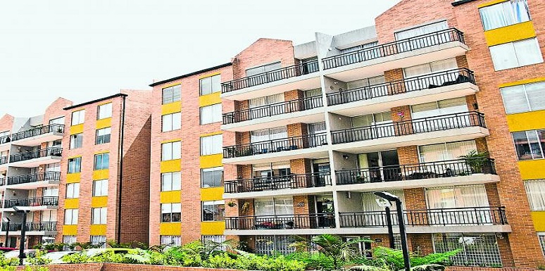 Edificio de ladrillos con balcones negros con ventanas amarillas