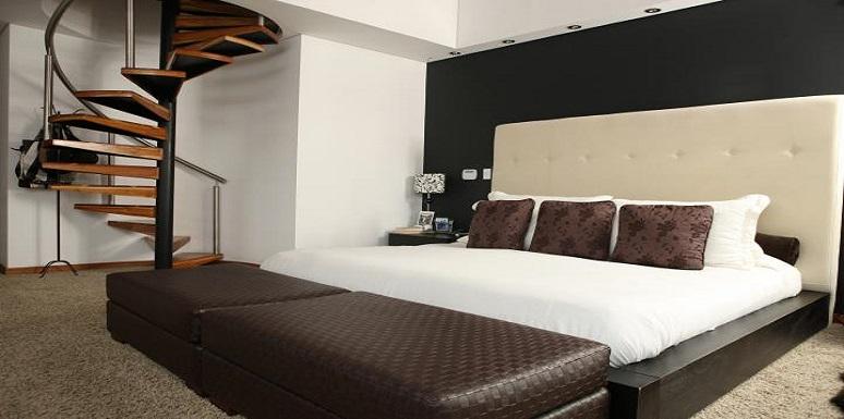 Habitación escalera caracol cama doble color beige, blanco y café