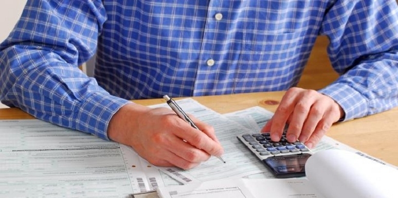 Hombre haciendo cuentas con papeles y calculadora