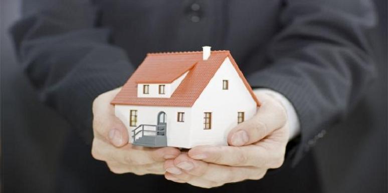 Hombre sosteniendo casa en sus manos