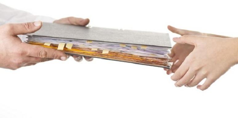Mano entregando carpeta con papeles a otra mano