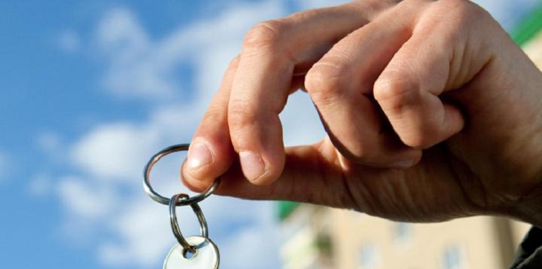 Mano sosteniendo llave con cielo de fondo 