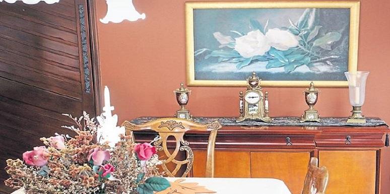 Mesa con adornos antiguos pared con cuadro con rosas blancas
