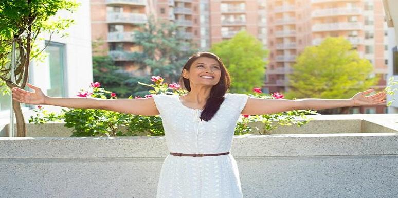 Mujer extendiendo los brazos delante de edificios
