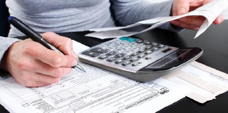 Mujer llenando formulario usando calculadora