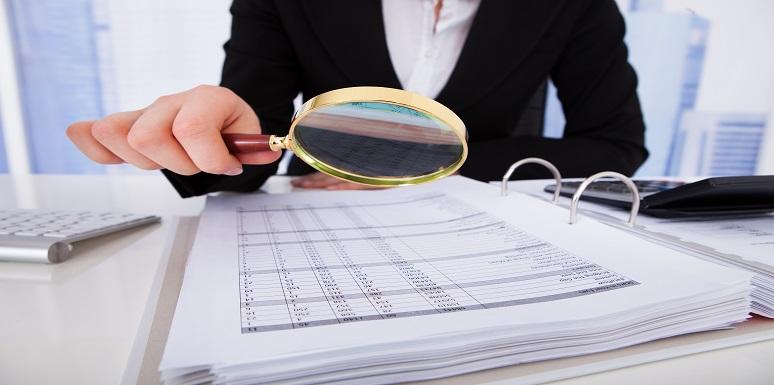 Mujer revisando con lupa documentos