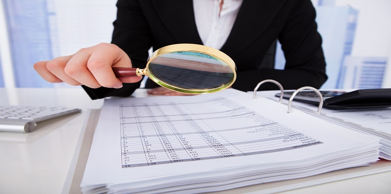 Mujer revisando con lupa documentos