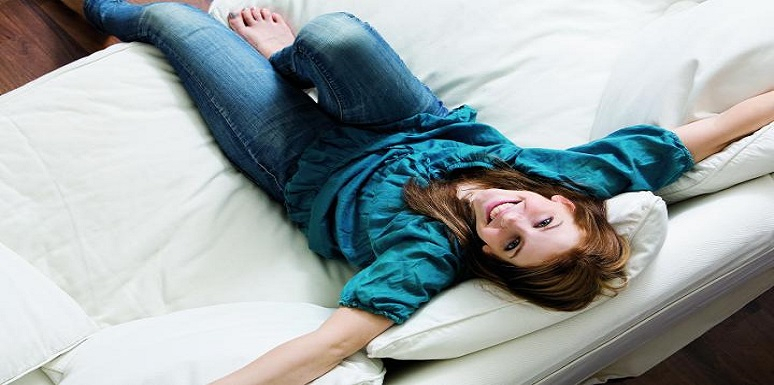 Mujer sentada en sofá con los brazos extendidos