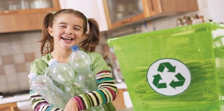 Niña con botellas de plástico junto a caneca con símbolo de reciclaje
