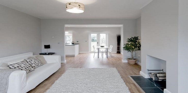 Sala con chimenea paredes tapete y sofá blanco