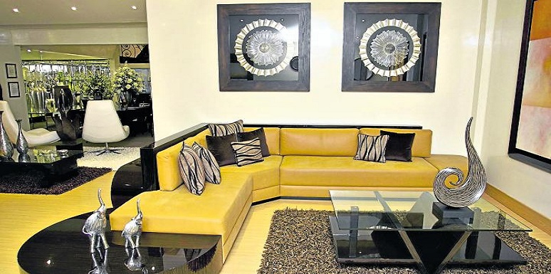 Sala sofá amarillo adornos plateados en mesa y paredes