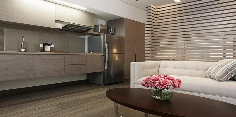 Sala con sofá blanco en frente de pequeña cocina